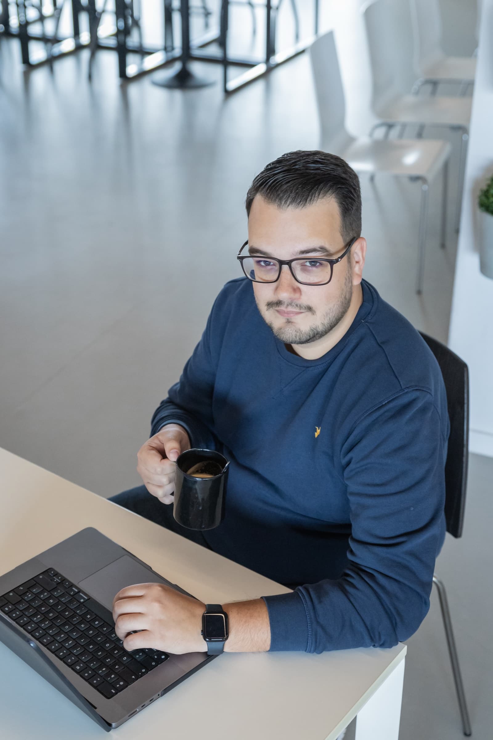Tyas aan zijn bureau met koffie en toetsenbord